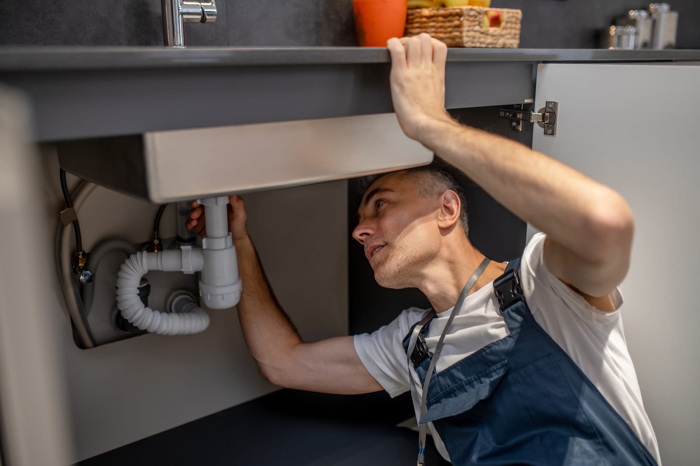 A plumber working underneath a kitchen sink